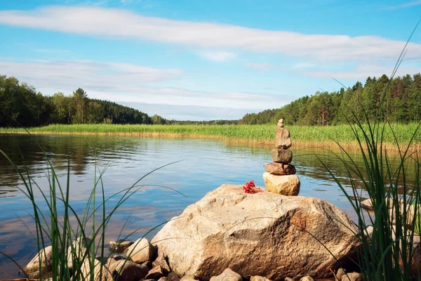 Malá pyramida kamenů a hromada jahodových bobulí na břehu jezera Ladoga. — Stock fotografie