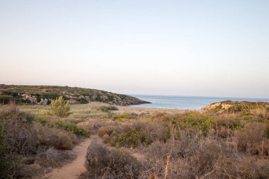 Gün batımında Calamosche plajı tepeden kumla kaplı.