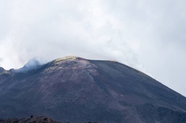 Etna Dağı 'nın yanı sıra sarı sülfür bölgeleri, volkanik kül, lav kayaları ve önceki patlamaların tozları. Su buharı ve dumanla karışık bulutlu dumanlı volkan.