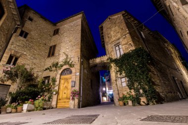 Tuğladan evler, ahşap bir kapı, yeşil ve çiçek açan bitkilerle dolu eski bir İtalyan kasabasının küçük meydanı. Toskana ve Umbria 'ya Seyahat