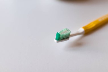 Beyaz yeşil tüylü diş fırçası ve beyaz arka planda sarı saplı