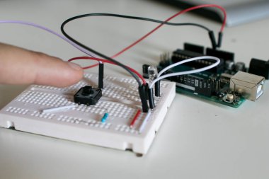 Elektronik prototipteki tek panelli düğmeye basan adam deney için yol gösterdi. Bilim, elektronik ve robotik alanlarında eğitim faaliyetleri