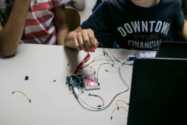 İki çocuk bir mikro kontrolör tarafından kontrol edilen kırmızı lazerle prototip devresi yapıyorlar. STEAM ve kodlama etkinliği