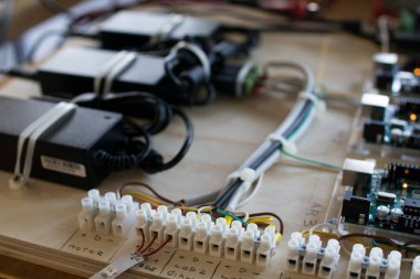 Etkileşimli ışıklandırma prototipinde LED şeritleri yöneten bir devre bağlantıları. Arka planda mikro denetleyici, çoklu metre ve güç kaynakları.