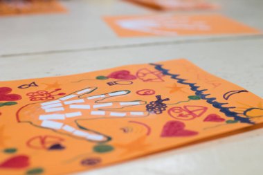 Çocuklar için bilimsel aktivite, el kemiklerinin çizimi ve kolajı. Süslü turuncu bir çarşafa bir el çizildi ve keçeli kalemlerle boyandı. STEAM öğretmek için yaratıcı etkinlik