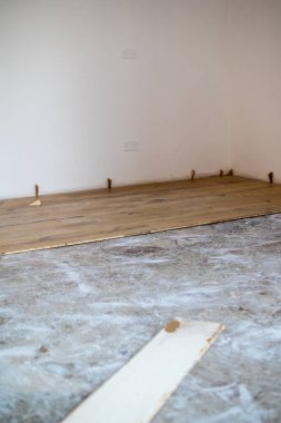 Önceden var olan mermer zemine meşe parke yerleştirilmiş. Yerdeki çalışma araçlarıyla aynı hizada tahtalar. Beyaz arkaplan duvarına eklenmiş boşluk takozları