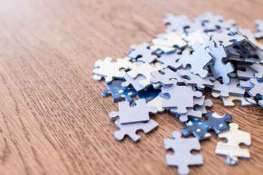 Ahşap bir masanın üzerindeki bulmacanın mavi fayansları. Liderliği, etkiyi, vizyonu ve karmaşık sorunların çözümünü belirten kavram. Bazı fayanslar üç boyutlu olarak en üste doğru sıralanır.