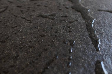 Çiğ ve sert siyah granit levha suyla ıslanmış. Siyah granit bir levha üzerine su damlaları ve bantlar, döşeme ve yapı malzemelerinde tazelik ve zarafet. Siyah taş ve su damlaları.