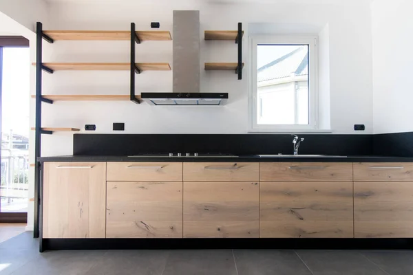 新造的木制厨房 不锈钢和黑色花岗岩刚刚建在一个新公寓里 室内工业设计 有外露的货架和深灰色的地板 黑色和无氧钢 图库图片