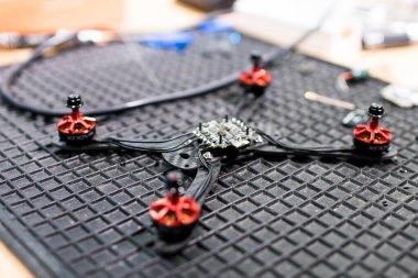 Merkezi kontrol ünitesi ve motorlarıyla onarılması için bir İHA 'nın çerçevesi açıldı. Bir çalışma masasında, bir kuadrikopter drone 'un şasisi. İnsansız hava aracı, mühendislik ve hobi teknolojisi faaliyeti