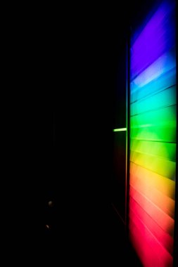 Prizmalardan oluşan parlak spektrum yansıyan plakalarla bir duvara yansıtılıyor. Siyah arkaplanda yapay gökkuşağı. Işığın birincil renkleri kırılma ile bölünür. Işık ve ışık spektrumlu bilimsel aktivite