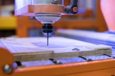 CNC değirmen makinesi ahşap bir masa oyarken. Kesici odun keserken bir bilgisayar tarafından kontrol ediliyor. FabLab için enstrümantasyon ve dijital imalat için uygun Makerspace.