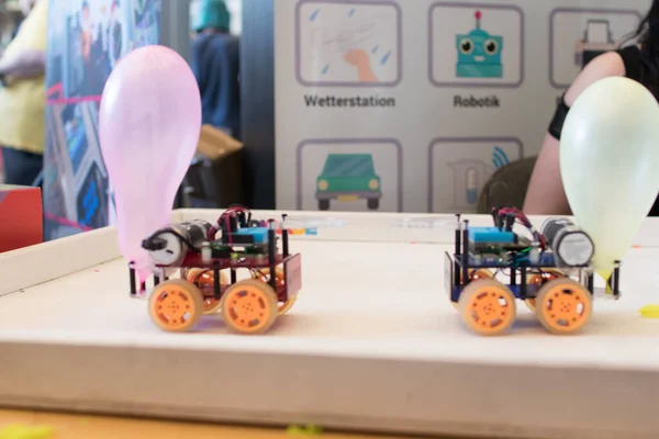 Robots with wheels fighting on a playground with a balloon on the back. Coding activities for children. STEAM and educational robotics in classroom. Robotics challenge for engineering kids game