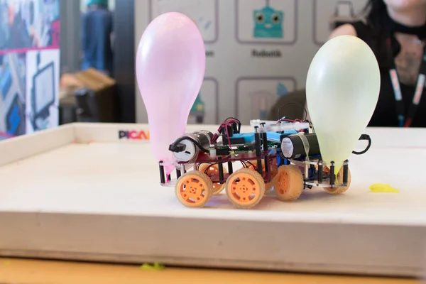 Robots with wheels fighting on a playground with a balloon on the back. Coding activities for children. STEAM and educational robotics in classroom. Robotics challenge for engineering kids game