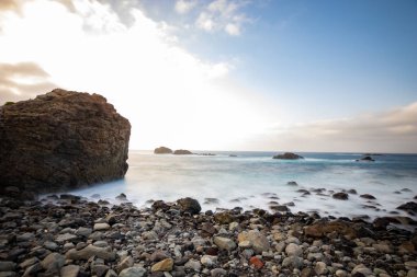 Deniz manzarası, günbatımında sahilin deniz manzarası, deniz, dağlar, kayalar, bulutlar ve yumuşak ışık dalgaları. Gün batımında Tenerife adası kıyısı ve denizi