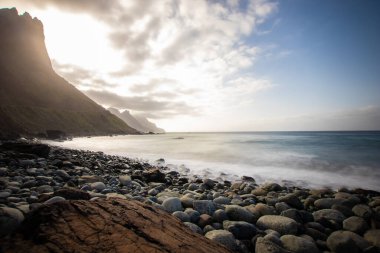 Deniz manzarası, günbatımında sahilin deniz manzarası, deniz, dağlar, kayalar, bulutlar ve yumuşak ışık dalgaları. Gün batımında Tenerife adası kıyısı ve denizi