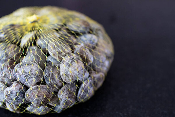 handful of "lupini" type clams on a black granite table ready to be cooked. raw food molluscs