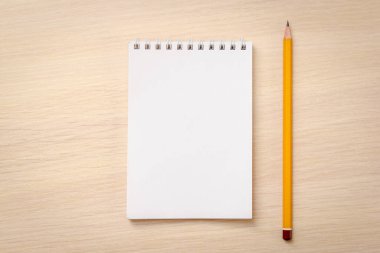 Ahşap zemin üzerinde boş defter ve kalem.