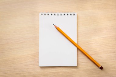 Ahşap zemin üzerinde boş defter ve kalem.