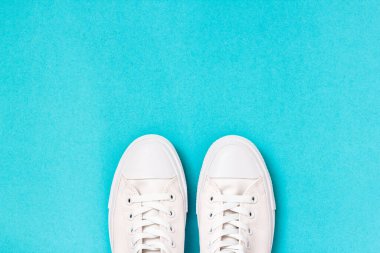 Mavi arka planda bir çift yeni beyaz spor ayakkabı. Üst görünüm.