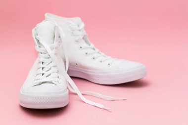 Pembe arka planda bir çift yeni beyaz spor ayakkabı..