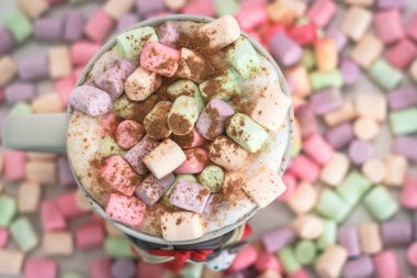 Renkli marşmelovların arka planında bir fincan kahve.