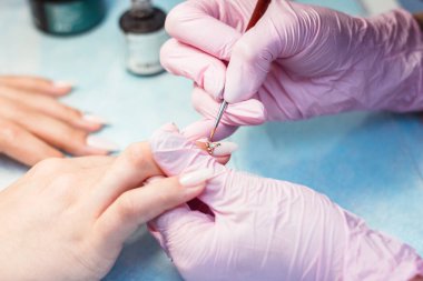 Manikür işlemini kapat. Profesyonel bir manikürcü tırnaklarına yapay elmas yapıştırır..