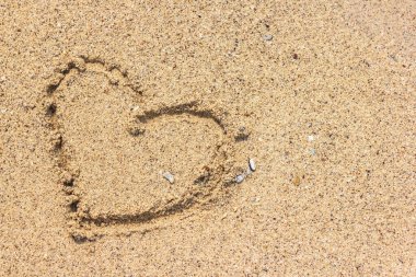 Kalp şekli kumsalda kumlara çizilmiş.