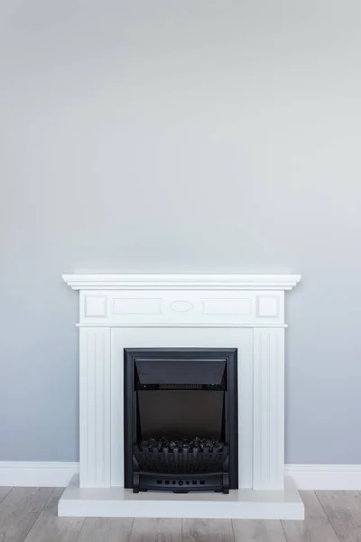 White wooden decorative electric fireplace. Interior photo on gray background. Place for a simple text.
