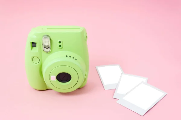 Green instant camera and ready-made photos on a pink background. Mockup.