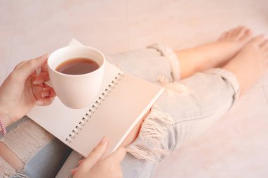 Kahve içen ve günlük için not defteri tutan bir kadın..