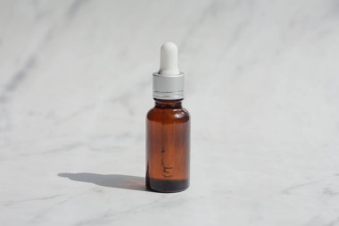 Yeşil ve kahverengi yüz maskesi esaslı yağ ya da beyaz mermer arka planda serum ambalajı. Cilt konsepti için güzellik kozmetik ürünü. Minimum ve lüks bir tarz. Işık ve gölge.