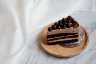 Beyaz mermer zemin üzerinde çikolata topu olan bir dilim çikolatalı pasta..