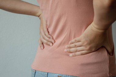 Genç Asyalı kadın sırtına dokunuyor ve sırtına, kalçasına, sağlık hizmetlerine ve tıbbi konseptine acı veriyor..