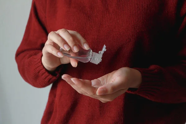 Close up woman hands using wash hand sanitizer gel dispenser, against  coronavirus or Covid-19 virus and other viruses. Healthcare concept. Red sweater.