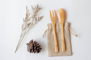 Yeniden kullanılabilen paslanmaz çelik kamışla bembeyaz arka planda doğal torba içinde tahta kaşık, çevre dostu ve sıfır atık konsepti..