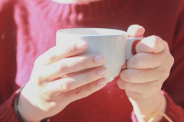 Elinde bir fincan kahve tutan kırmızı bir kadın..