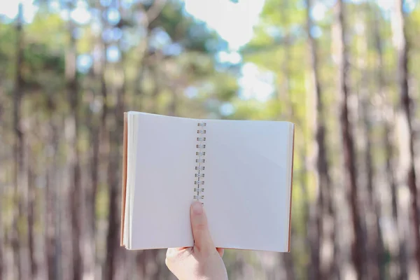 Mano Che Tiene Taccuino Carta Bianco Sullo Sfondo Della Foresta — Foto Stock