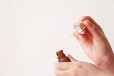 Beyaz arka planda yüz kremi ya da serum ambalajı tutan kadın elleri. Cilt bakımı için güzellik kozmetik ürünü.