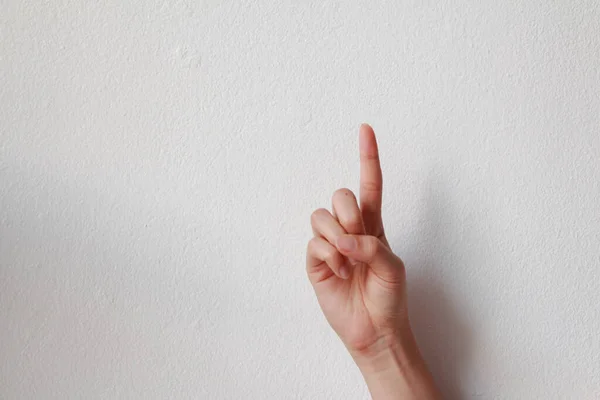 female hand index finger pointing up on white background.