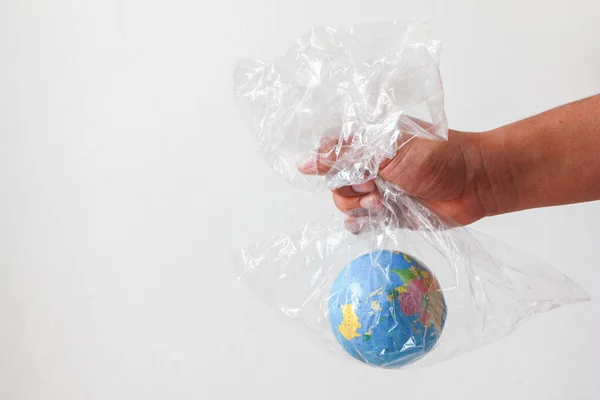 The man\'s hand holds the earth in a plastic bag on white background. Concept of an environmental disaster