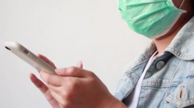 Kadınlar koruyucu maske takar ve akıllı telefon kullanır..