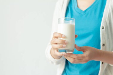 Beyaz arka planda bir bardak taze süt tutan bir kadın..