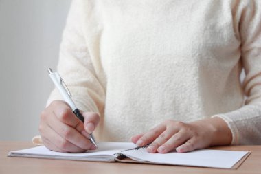 Not defterine kalem yazan kadın eli. Sarı kazaklı kadın..