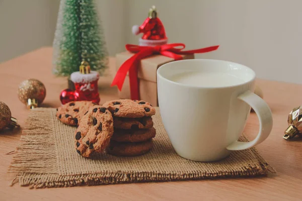 White mug with Chocolate cookies and gift box on wood table. Christmas holiday concept.