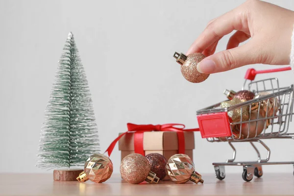 Mano Poniendo Decoraciones Navideñas Brillantes Carrito Compras Sobre Fondo Blanco —  Fotos de Stock