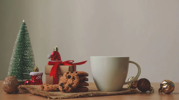 White mug with Chocolate cookies and Gift box on wood table. Christmas.