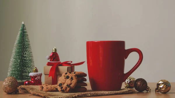 Red mug with Chocolate cookies and Gift box on wood table. Christmas.