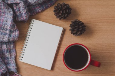 Bir fincan kahve ve defter ahşap masada.