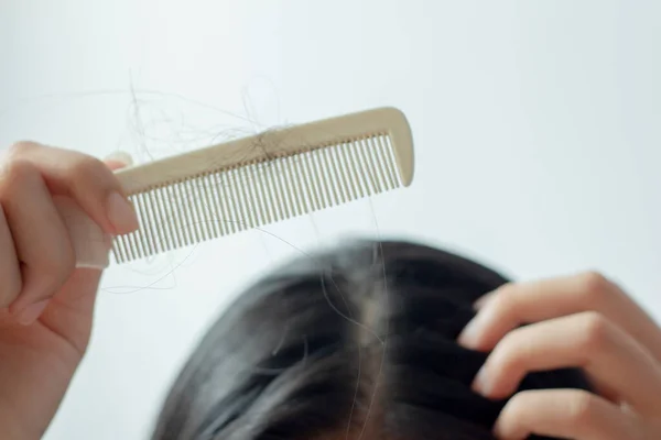 Young Asian woman with hair comb on white background, closeup problem hair.